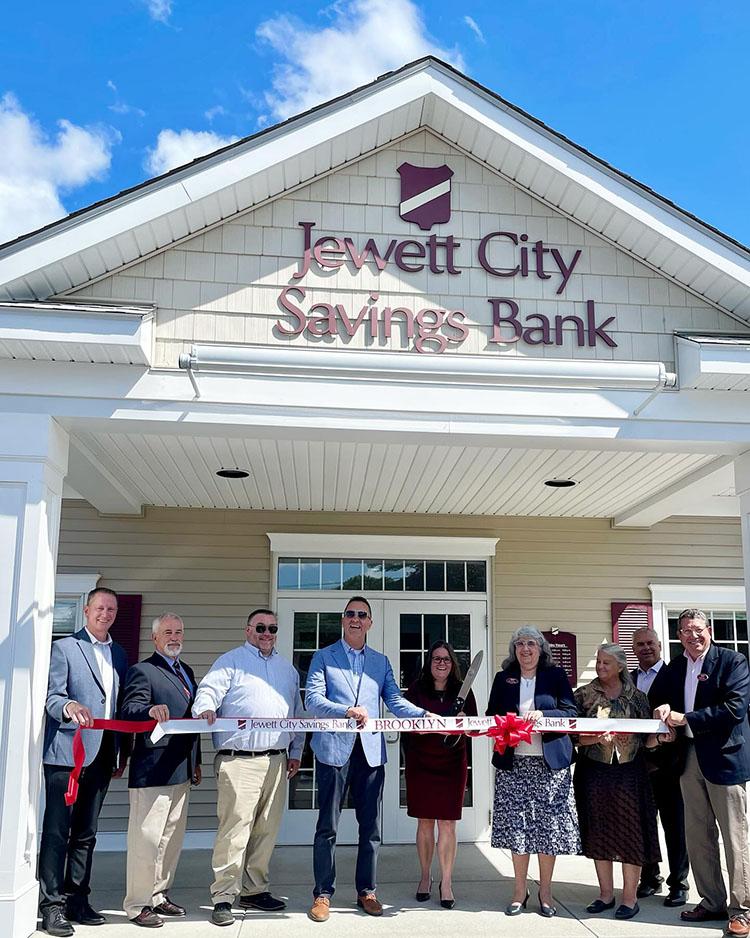 A group of individuals standing outside of the Brooklyn branch, holding a white ribbon for their ribbon cutting ceremony