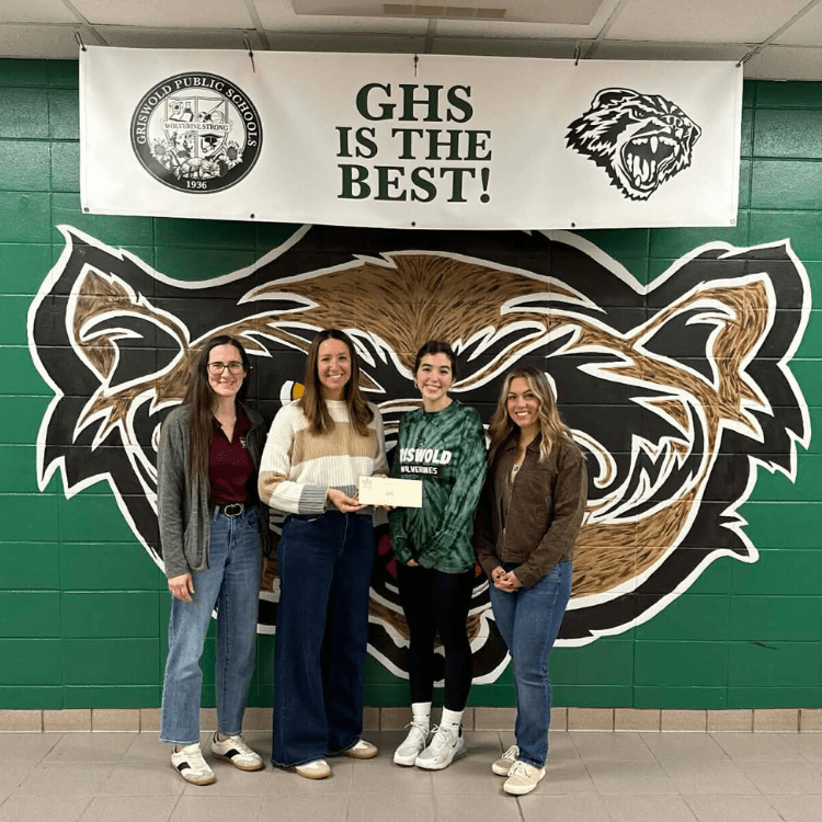 Jewett City Savings Bank member standing alongside Griswold Pride Project Coordinator and Student Leadership members holding a check.