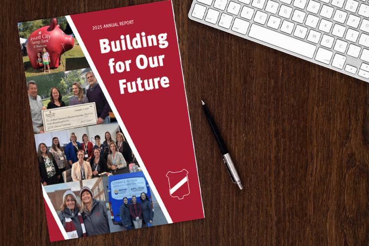 "Building for Our Future" 2025 Annual Report on a desk with pen and keyboard.