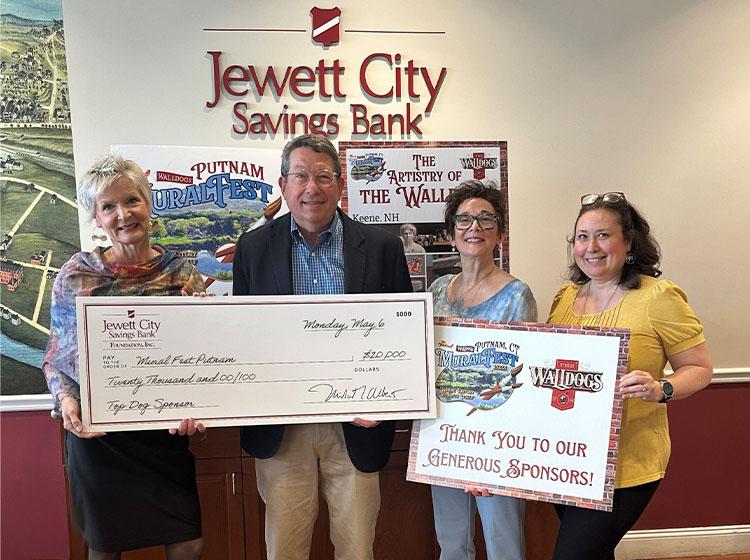 A group photo of four people holding up a big check.